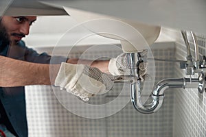 Close up of indian plumber is repairing faucet of a sink at bathroom using adjustable wrench