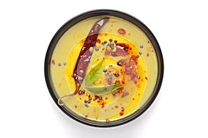 Close-up of Indian traditional kadhi or kadi pakora yogurt and gram flour and turmeric served hot in a black bowl.