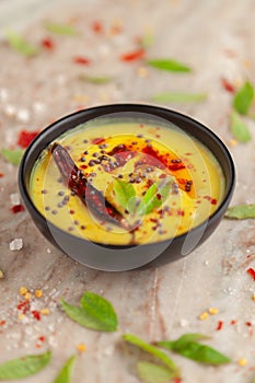 Close-up of Indian traditional kadhi or kadi pakora yogurt and gram flour and turmeric served hot in a  black bowl