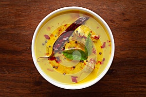 Close-up of Indian traditional kadhi or kadi pakora yogurt and gram flour and turmeric served hot in a bowl. Over a wooden photo