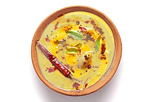 Close-up of Indian traditional kadhi or kadi pakora yogurt and gram flour and turmeric served hot in a clay bowl.
