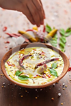 Close-up of Indian traditional kadhi or kadi pakora yogurt and gram flour and turmeric served hot in a clay bowl.