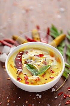 Close-up of Indian traditional kadhi or kadi pakora yogurt and gram flour and turmeric served hot in a clay bowl. photo