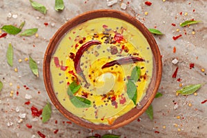 Close-up of Indian traditional kadhi or kadi pakora yogurt and gram flour and turmeric served hot in a clay bowl. garnished with f photo