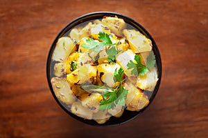 Close-up of Indian vegetarian classic dish Jeera Aloo - Potatoes Flavored with Cumin  garnished with green coriander fresh leaves.