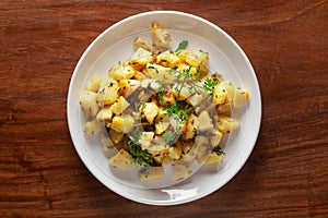 Close-up of Indian vegetarian classic dish Jeera Aloo - Potatoes Flavored with Cumin garnished with green coriander fresh leaves.