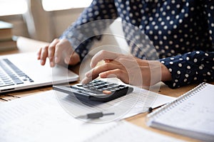 Close up Indian woman planning budget, using calculator and laptop