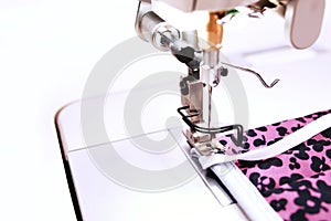 Close up on individual pink protective cotton face mask with screen print produced with an industrial high-speed sewing machine