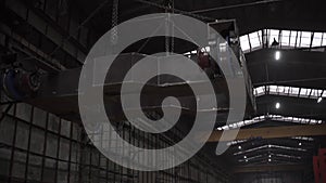 Close up of an indoor factory overhead crane transporting heavy industrial trolley. Clip. View inside of working shop at