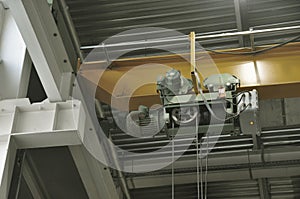 Close up of an indoor factory overhead crane on a yellow beam