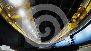 Close up of an indoor factory overhead crane on a yellow beam with heavy cargo