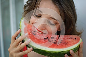 Close up indoors portrait of beautiful woman with short hair and sensual lips eating a piece of watermelon. Hedonism