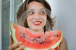 Close up indoors portrait of beautiful woman with short hair and sensual lips eating a piece of watermelon. Hedonism photo