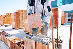 Close up of industrial bricklayer installing bricks on construction site