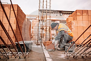 Close up of industrial bricklayer installing bricks on construction site