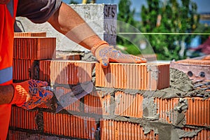 Close up of industrial bricklayer installing bricks on construction site. worker with bricks