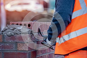 Close up of industrial bricklayer laying bricks on cement mix