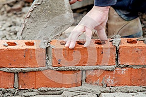 Close up of industrial bricklayer laying bricks on cement mix on construction site