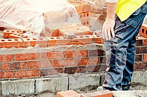 Close up of industrial bricklayer laying bricks on cement mix on construction site