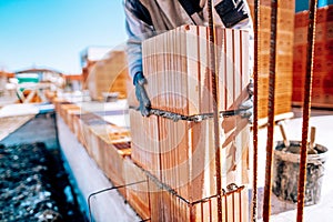Close up of industrial bricklayer worker installing bricks on construction site
