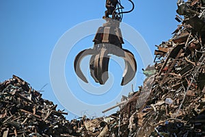 Close up industrial claw machine, move scrap metal in the landfill.