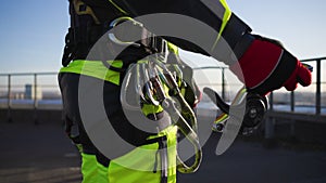 Close-up of an industrial climber unfastens the trigger device from the loop of the safety system and jumps to the