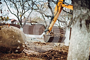 Close up of industrial mini excavator scoop moving earth and doing landscaping works