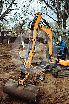 Close up of industrial mini excavator scoop moving earth and doing landscaping works