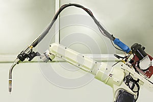 Close up industrial weld robot arm with mig electrode holder or torch for industrial at factory.