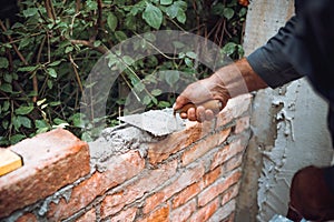 Close up of industrial worker, bricklayer installing bricks on exterior walls at construction site