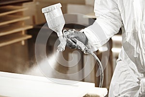 Close-up of industrial worker using paint gun or spray gun for applying paint, airless spraying.