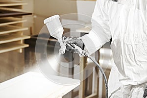 Close-up of industrial worker using paint gun or spray gun for applying paint, airless spraying.