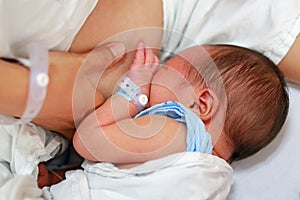 Close-up infant baby feeding from mother breastfeeding her newborn child on the hospital bed