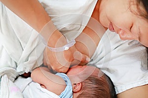 Close-up infant baby feeding from mother breastfeeding her newborn child on the hospital bed