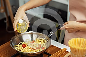 Close up influencer cooking spaghetti mix ingredient to frying pan. Postulate.