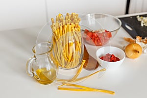 Close-up ingredients for cooking bolognese pasta: macaroni, tomatoes, olive oil and onion. Preparing traditional italian