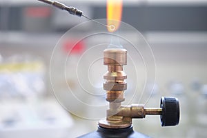 Close up of inoculation loop being sterilized in flame of gas bunsen burner in a laboratory