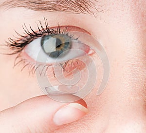 Close up of inserting contact lens in female eye