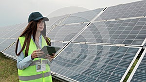 Close up inspector engineer woman walk on renewable energy station with digital tablet PC and checking solar panels