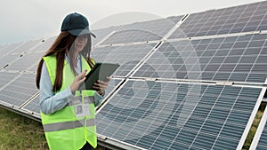 Close up inspector engineer woman walk on renewable energy station with digital tablet PC and checking solar panels