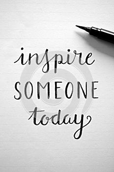 Close-up of `INSPIRE SOMEONE TODAY` hand-lettered in notebook