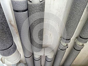 Close-up of insulated plumbing pipes. Insulated Pipes in Public Restroom