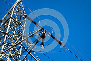Close-up of insulators on high voltage pylons against the background of blue sky.