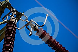 Close-up of insulators on high voltage pylons against the background of blue sky.