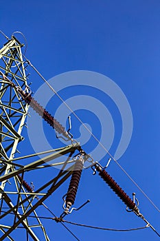 Close-up of insulators on high voltage pylons against the background of blue sky.