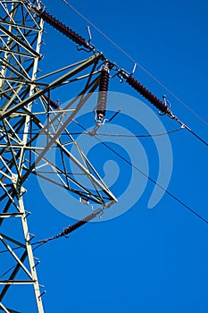 Close-up of insulators on high voltage pylons against the background of blue sky.