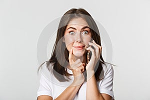 Close-up of intrigued smiling girl talking on smartphone with tempted expression