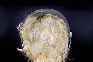 Close up of isolated back of the head of caucasian woman with blonde curly hair and black headphones, black background
