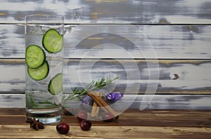 Close up of isolated cocktail glass with gin tonic cucumber slices, cinnamon, lavender, rosemary, cranberries botanicals. wooden