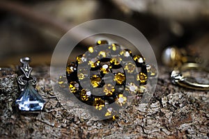 Close up of isolated old vintage brooch with yellow citrine quartz gemstones on natural tree trunk bark background